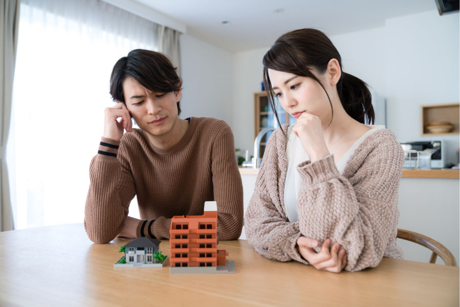 住宅の模型をテーブルに置いて悩む二人