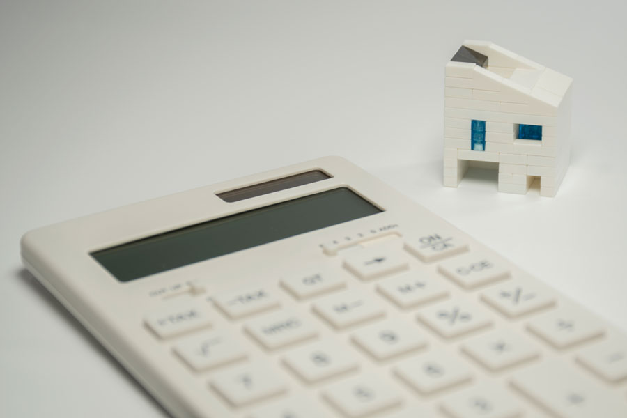 白い電卓と、ブロックでできた家の模型