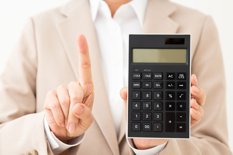 電卓を持って人差し指を立てるスーツ姿の人