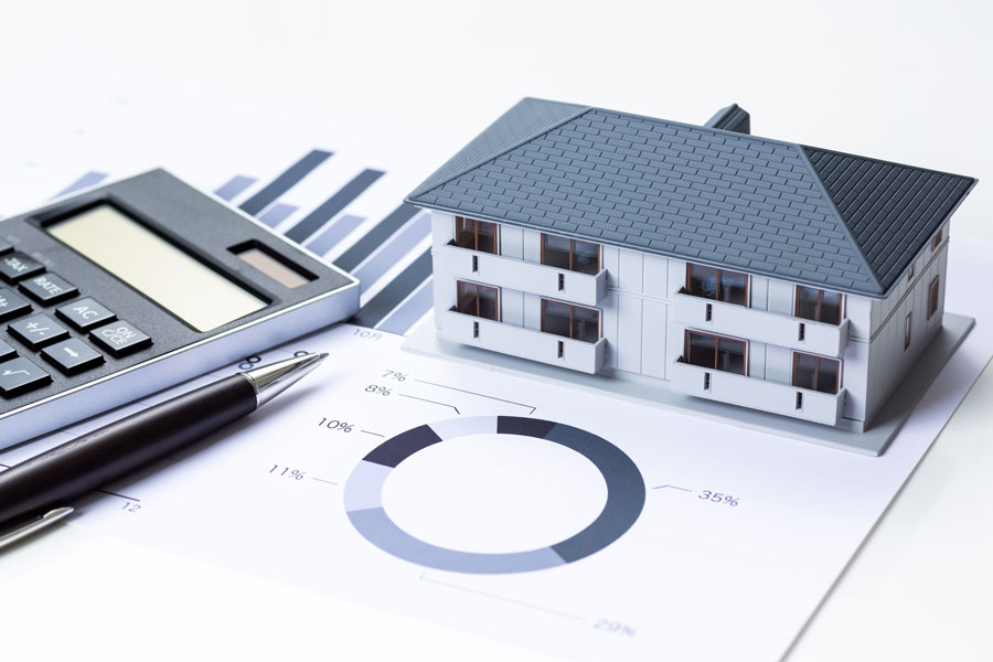 住宅の模型と円グラフの描かれた書類、電卓