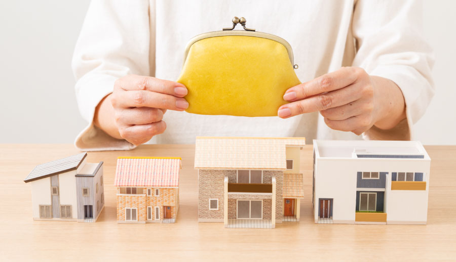 家の模型と財布を持つ人の手