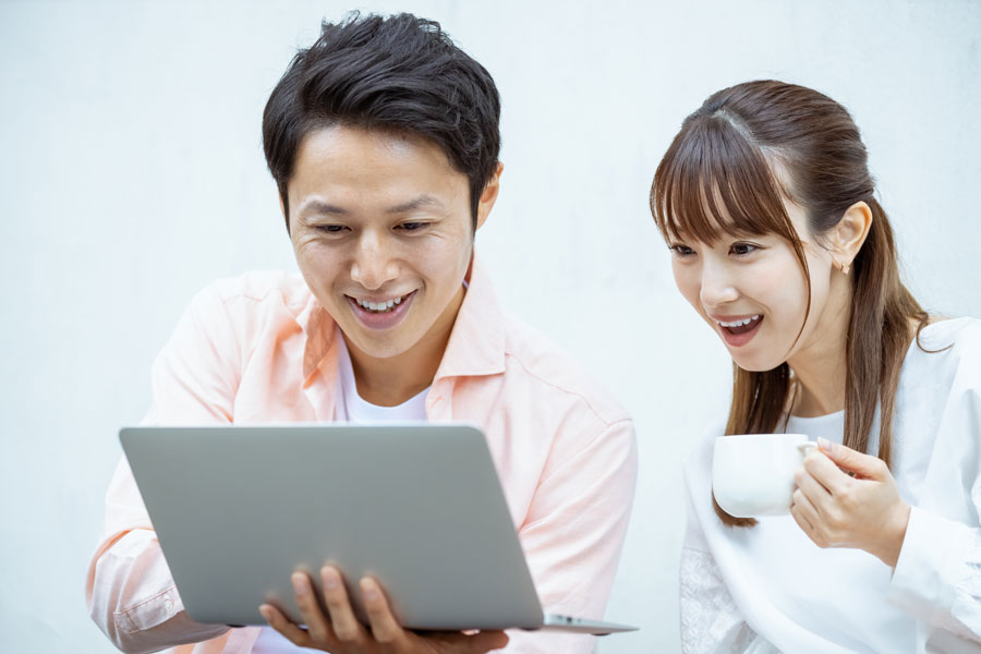 ノートパソコンの画面を一緒に見ている若い男女