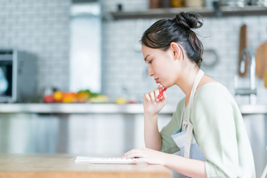 ノートと電卓を前に悩む人