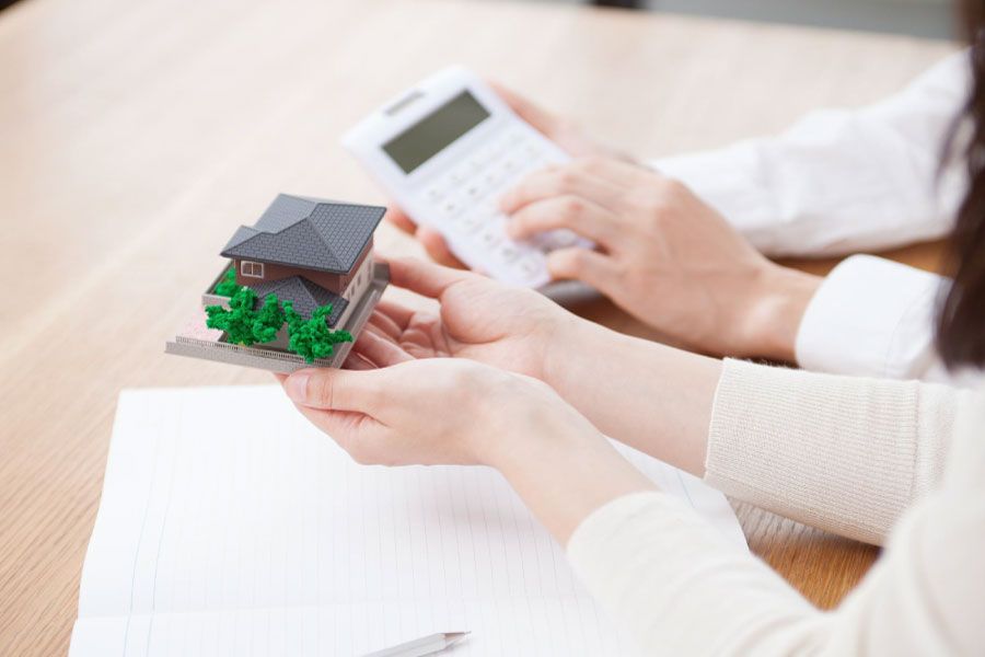 住宅の模型と電卓を持って話し合う2人