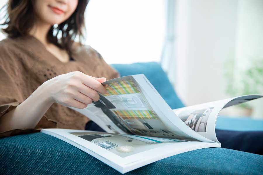 ソファで住宅のカタログを見る人
