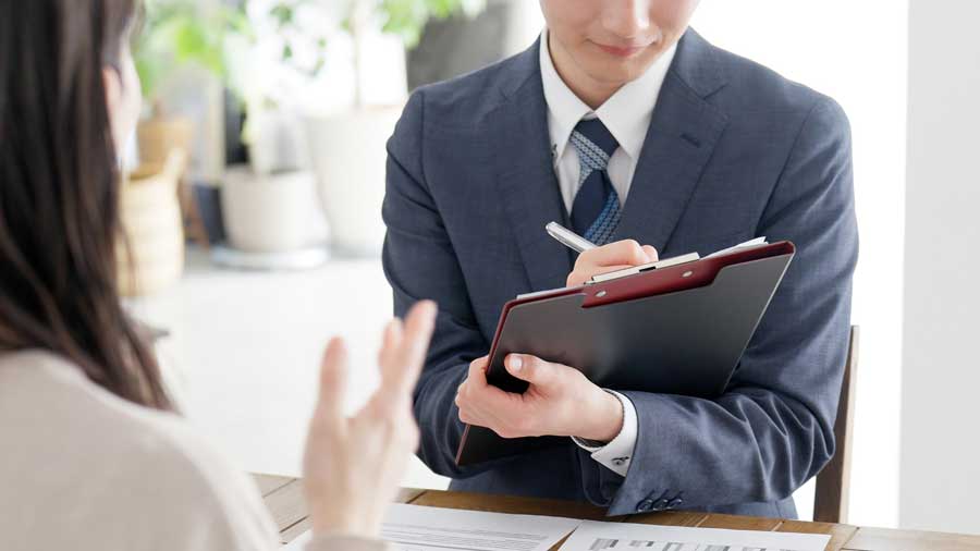 お客さまのヒアリングをするスーツのビジネスパーソン