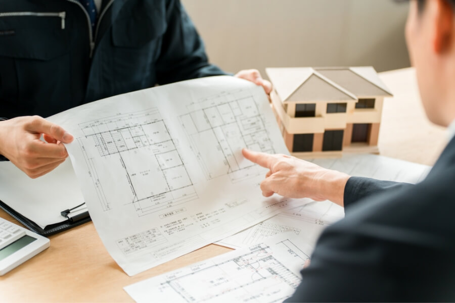 設計図を見ながら建築の相談をする人々