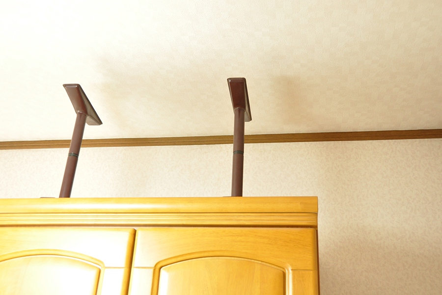 家具の上部を突っ張り棒で天井に固定している様子