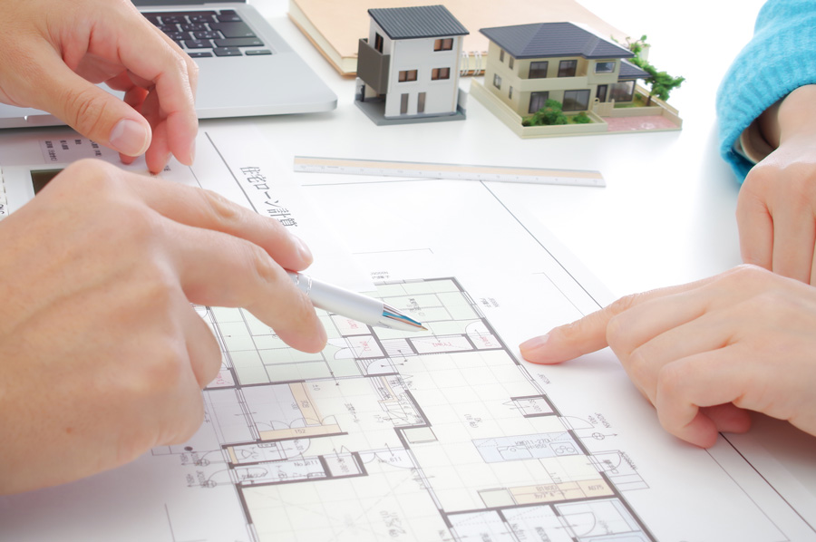 間取り図を挟んで話し合う2人の手元