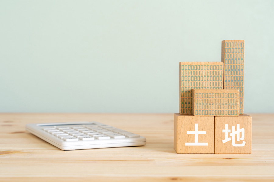 「土地」と書かれたウッドブロックと電卓