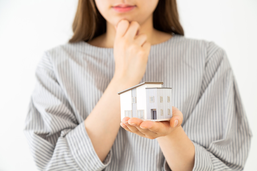 住宅の模型を持って疑問を持つ人